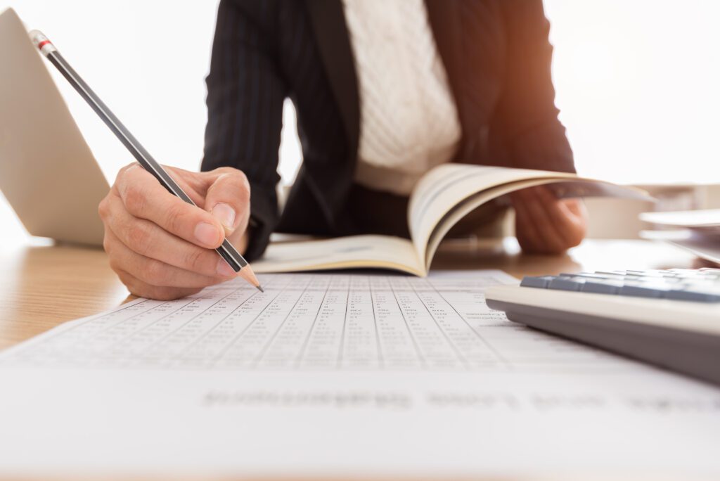 Person analyzing documents and taking notes.